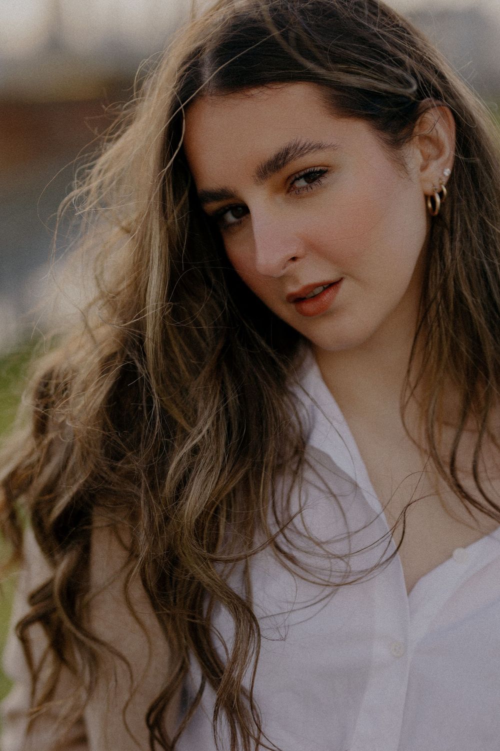 Warm-toned portrait with flowing hair and classic white shirt styling.