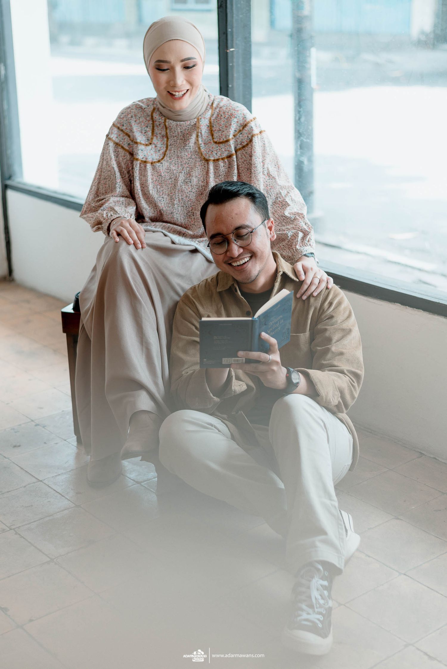 A tender moment captured as a couple reads together in a bright, minimalist setting.