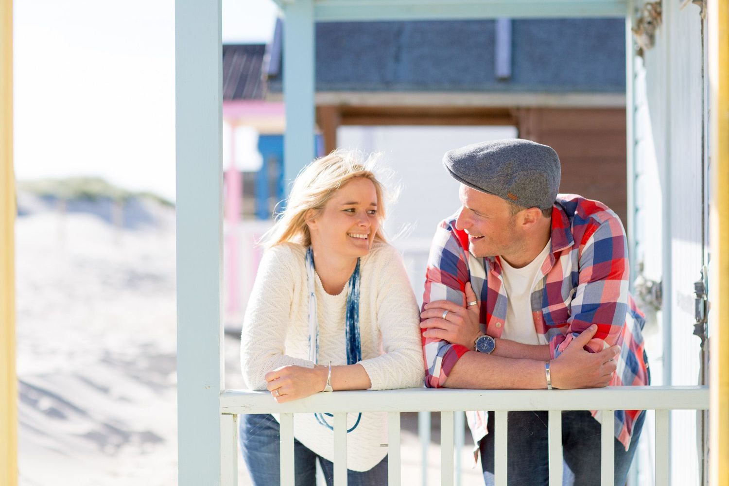 A couple shares a happy moment on a beach house porch during a sunny day.