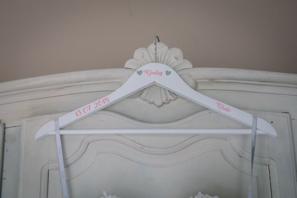 A decorative white wedding dress hanger displayed on an elegant vintage wardrobe.