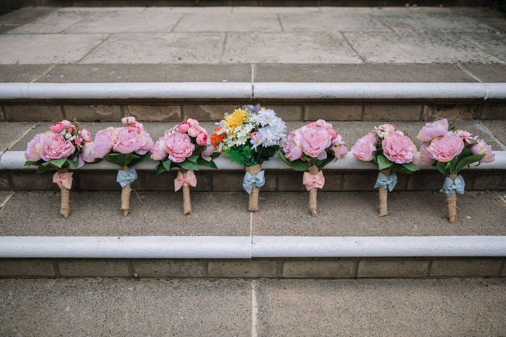 Row of pink and white floral wedding bouquets arranged on concrete steps.
