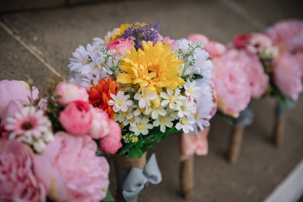 A vibrant floral arrangement featuring yellow, pink, and purple blooms in rustic wedding decor.