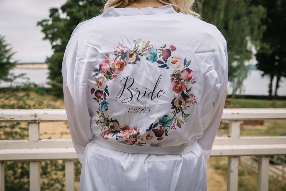 White satin robe with floral 'Bride' design embroidered on the back.
