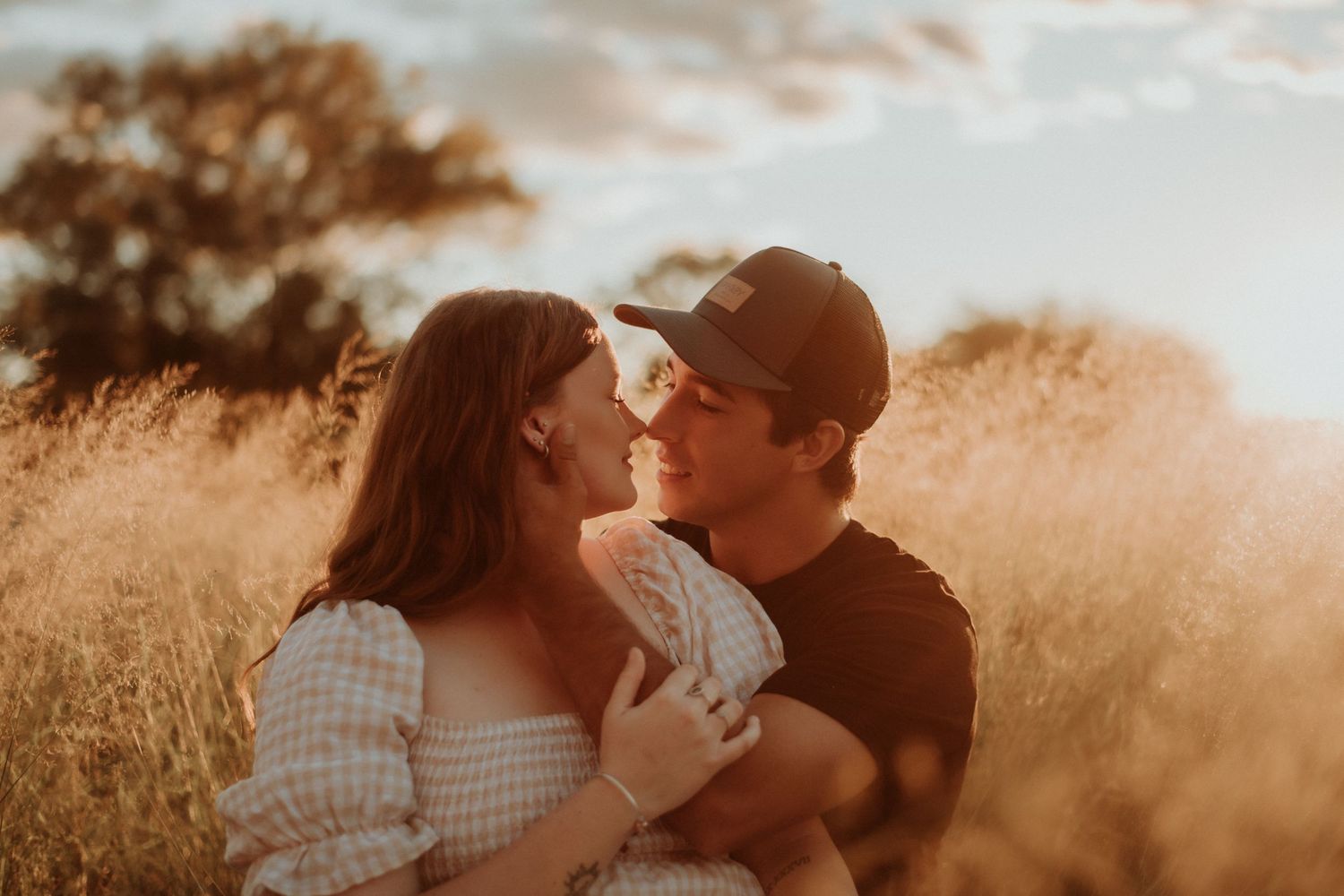 Warm sunset portrait of a couple sharing an intimate moment in tall grass.