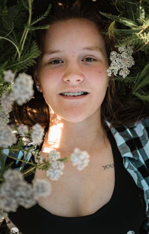 A nature portrait surrounded by white Queen Anne's Lace flowers and greenery with natural sunlight.