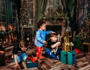 Christmas themed indoor setting with children opening presents near decorated trees and lanterns.