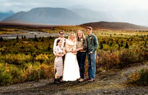 Wedding party poses together in Alaskan tundra with mountains in the background.
