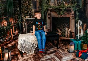 Child sitting on decorative table in Christmas themed room with lanterns and holiday decorations.
