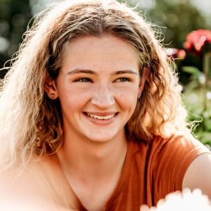 A sunny outdoor portrait surrounded by flowers and natural lighting.