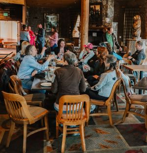 Large group enjoying a casual gathering at wooden tables in a rustic restaurant setting.