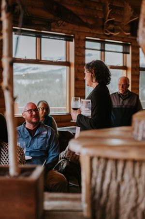 People gathered in a rustic cabin lounge area with mountain views through large windows.