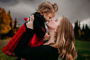 An intimate moment between parent and child against a dramatic mountain backdrop.