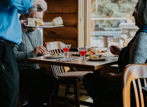 Diners seated at a restaurant table with food and drinks being served.