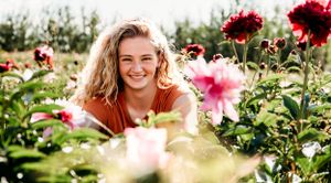 A joyful summer portrait among blooming pink and red flowers in a garden.