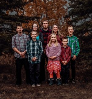 A group portrait against an autumn forest backdrop with evergreen trees and warm fall colors.