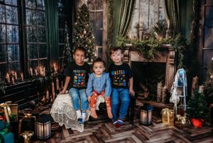Children sitting in a festive holiday setting with Christmas trees, lanterns and decorative elements.
