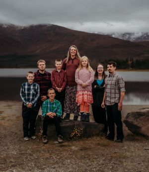 Group photo by mountain lake with autumn colors and cloudy sky.