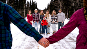 A winter family photo with hands holding in foreground framing the group.