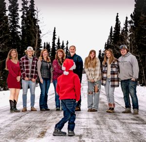 A creative winter family photo with one member standing apart on a snowy path.