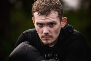 Dramatic close-up portrait against dark background.