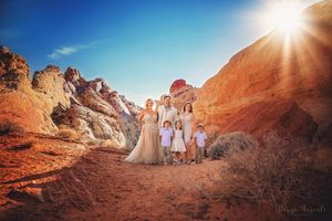Family group photo amid stunning red rock formations in a desert landscape.
