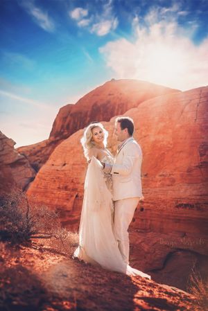 Elegant wedding couple poses against dramatic red rock cliffs during golden hour.