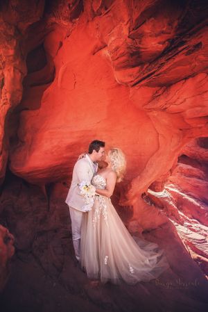 Romantic wedding photography in a natural red rock cavern with dramatic lighting.