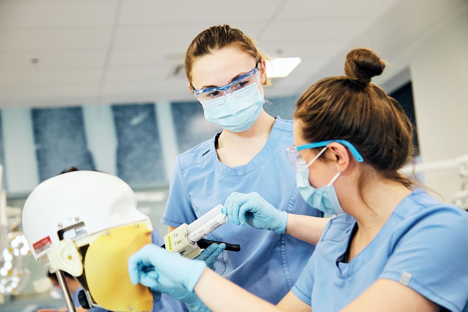 Female dental student wearing a mask engaged in conversation with another female student