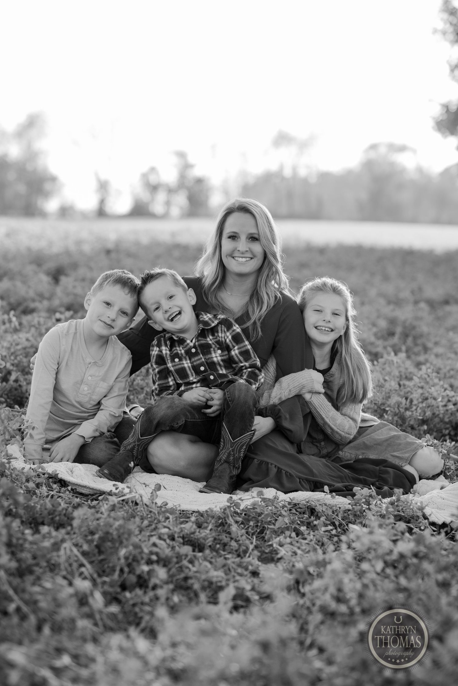 Black and white family portrait of a group sitting close together in a field.