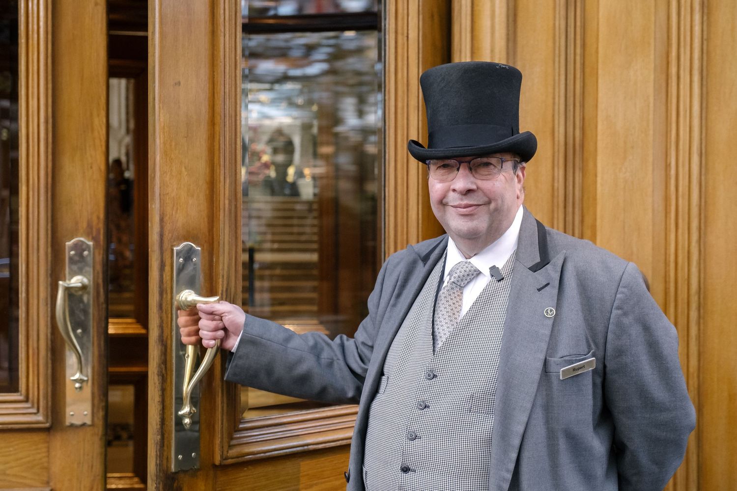 A porter in a top hat opening the door of Old Marylebone Town Hall, London.
