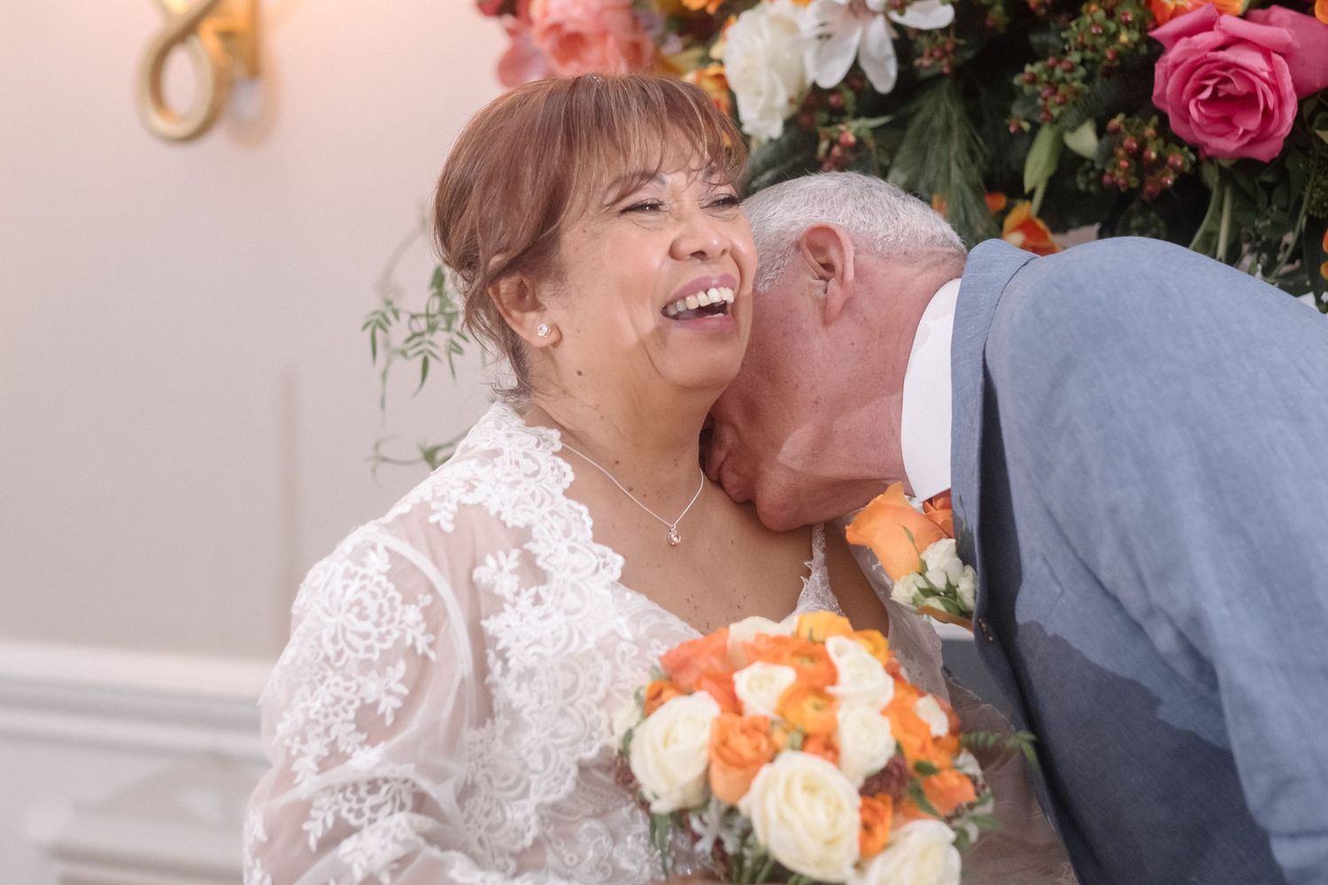 A groom kisses his bride's neck at a London wedding.