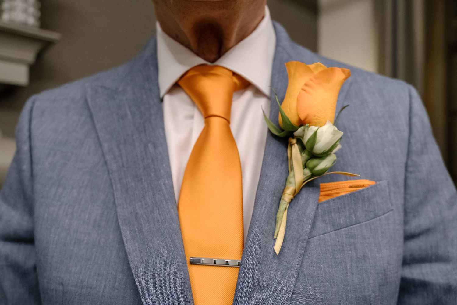 A close up of the groom's orange tie and boutonniere.