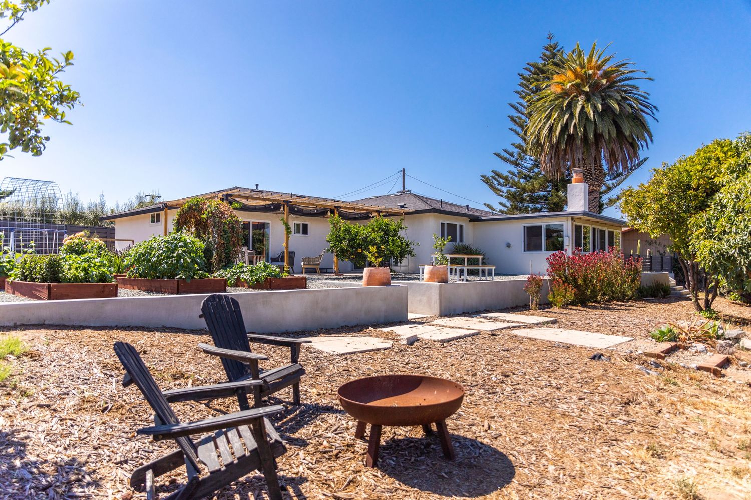 Ranch house with desert landscaping and outdoor seating area featuring fire pit.