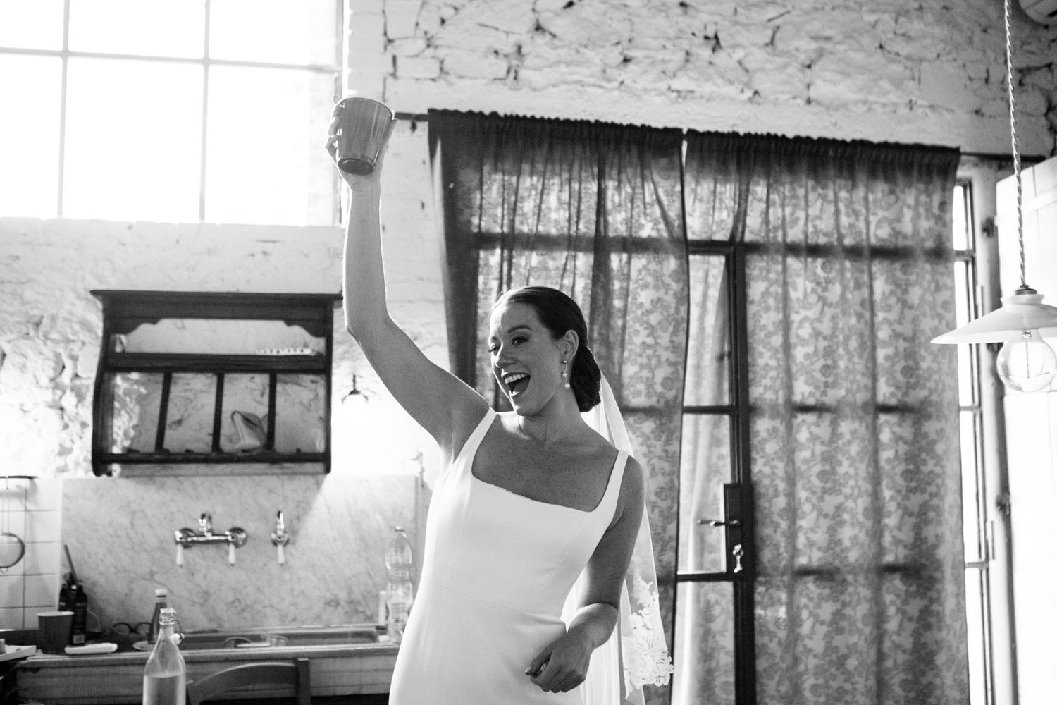 A bride raises a plastic cup to toast before her wedding.