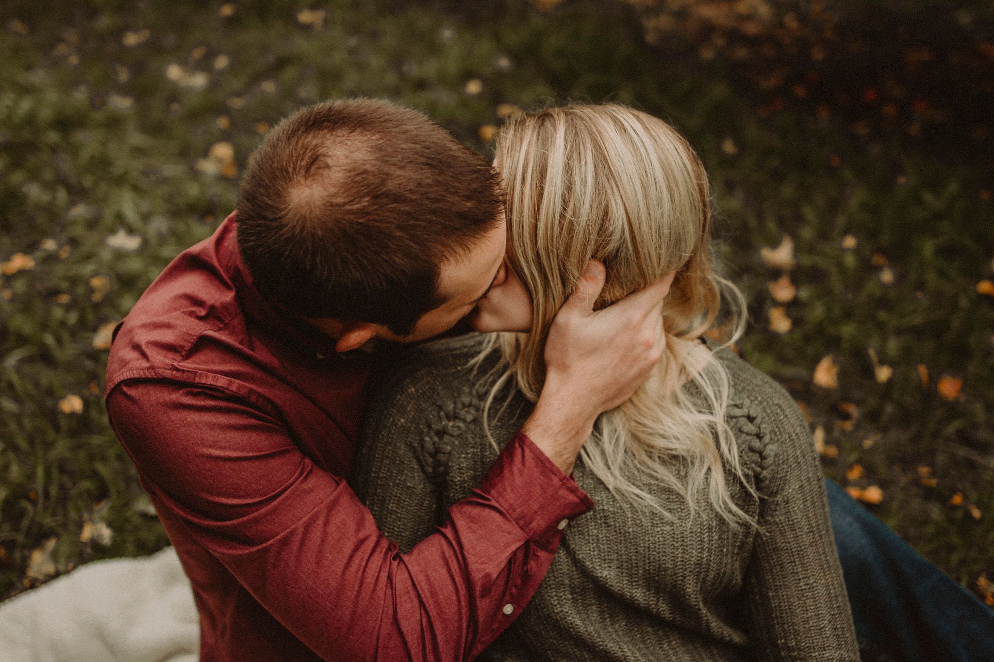 Intimate moment captured between couple during fall photo session in orchard.