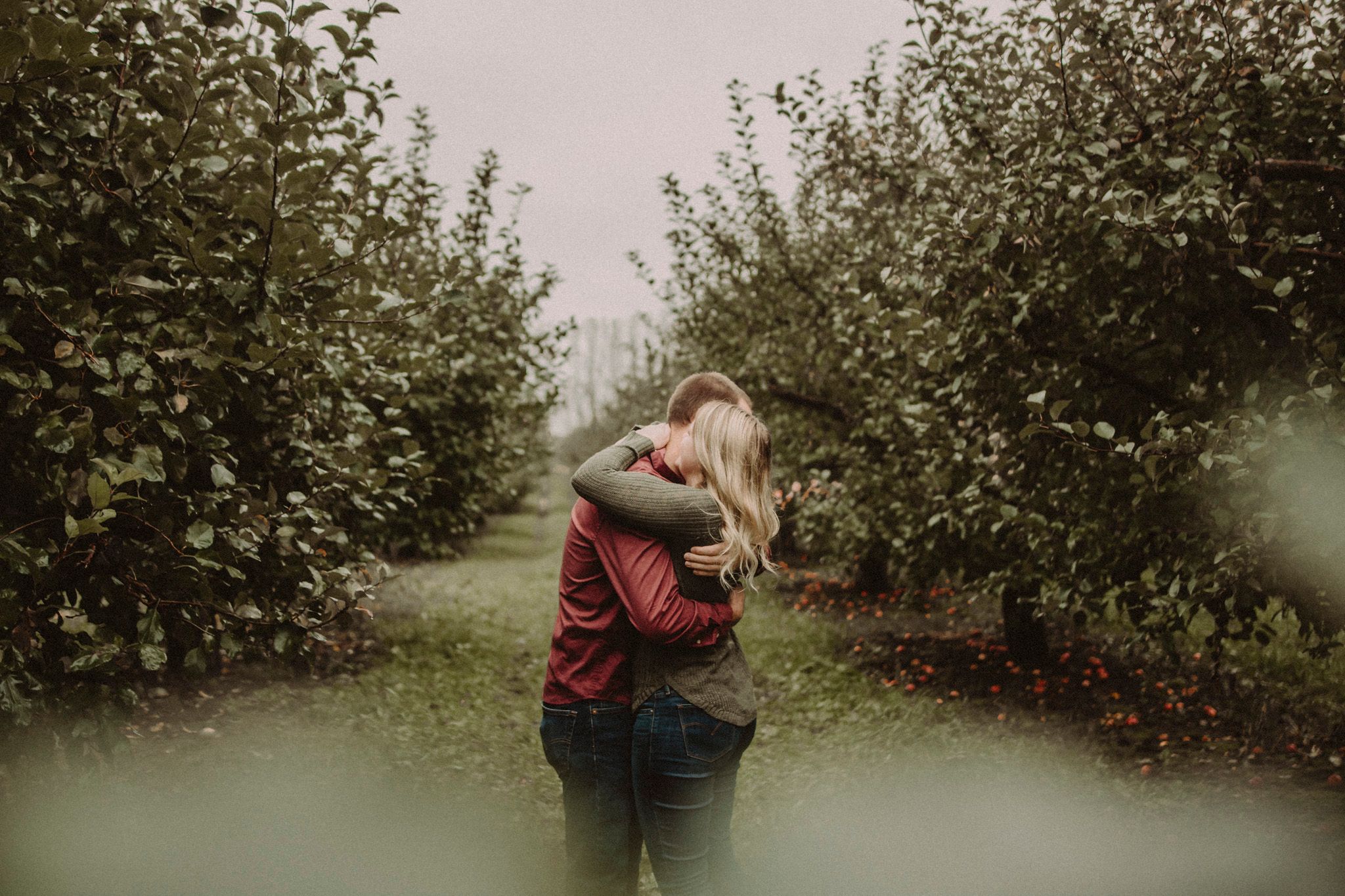 Intimate embrace between couple in an apple orchard during fall season.
