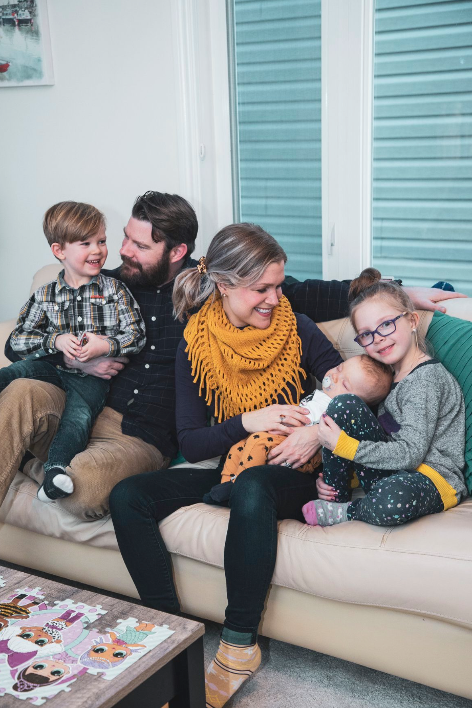 a family in their home all cuddled up on the couch looking at one another