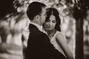 Romantic black and white portrait of couple under tree canopy.