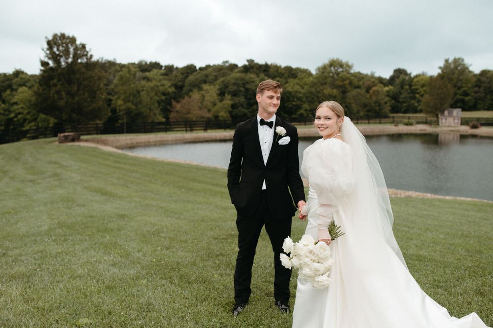 Wedding couple poses on a hillside overlooking a lake on their special day.