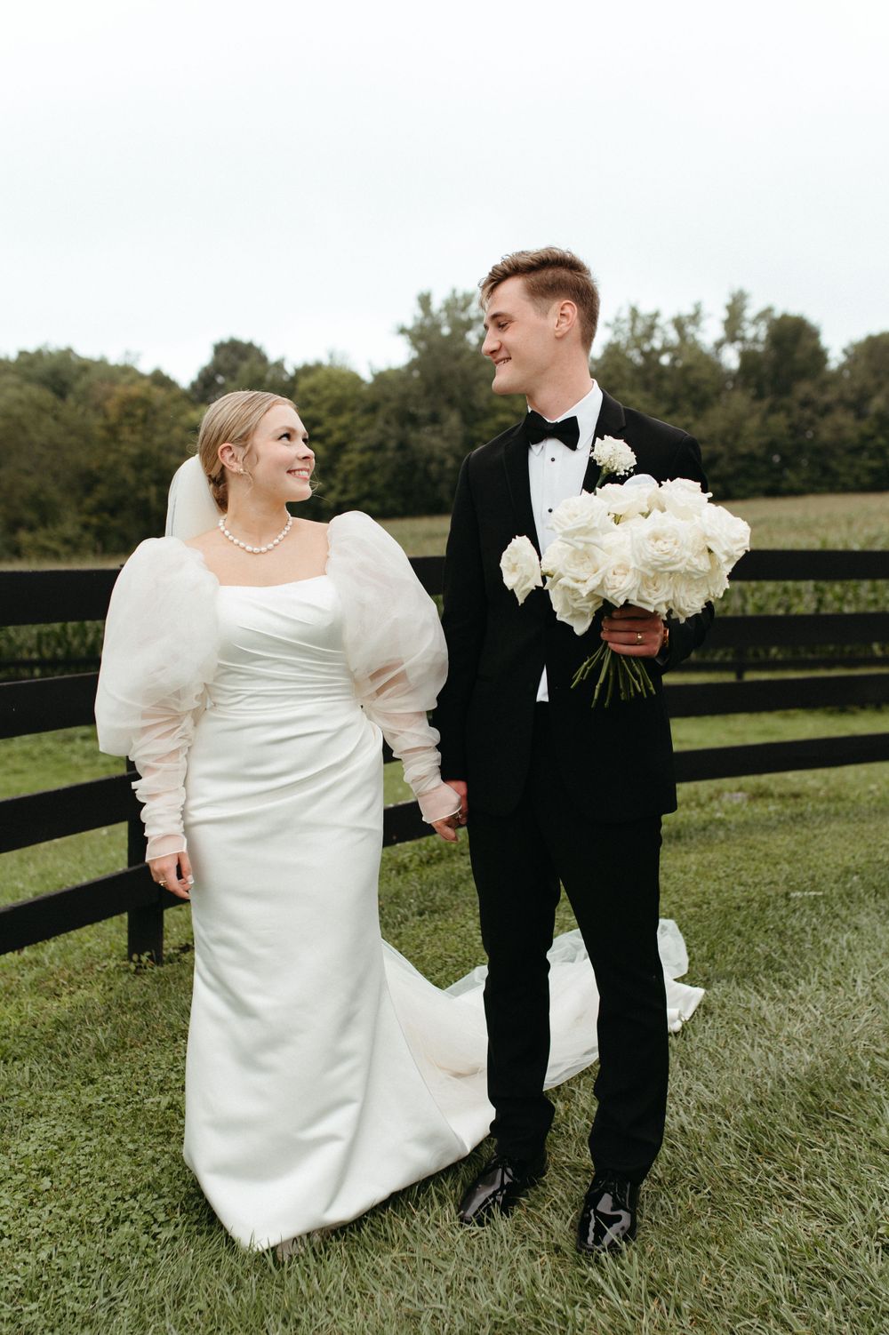 Couple shares a moment on their wedding day near rustic wooden fence.