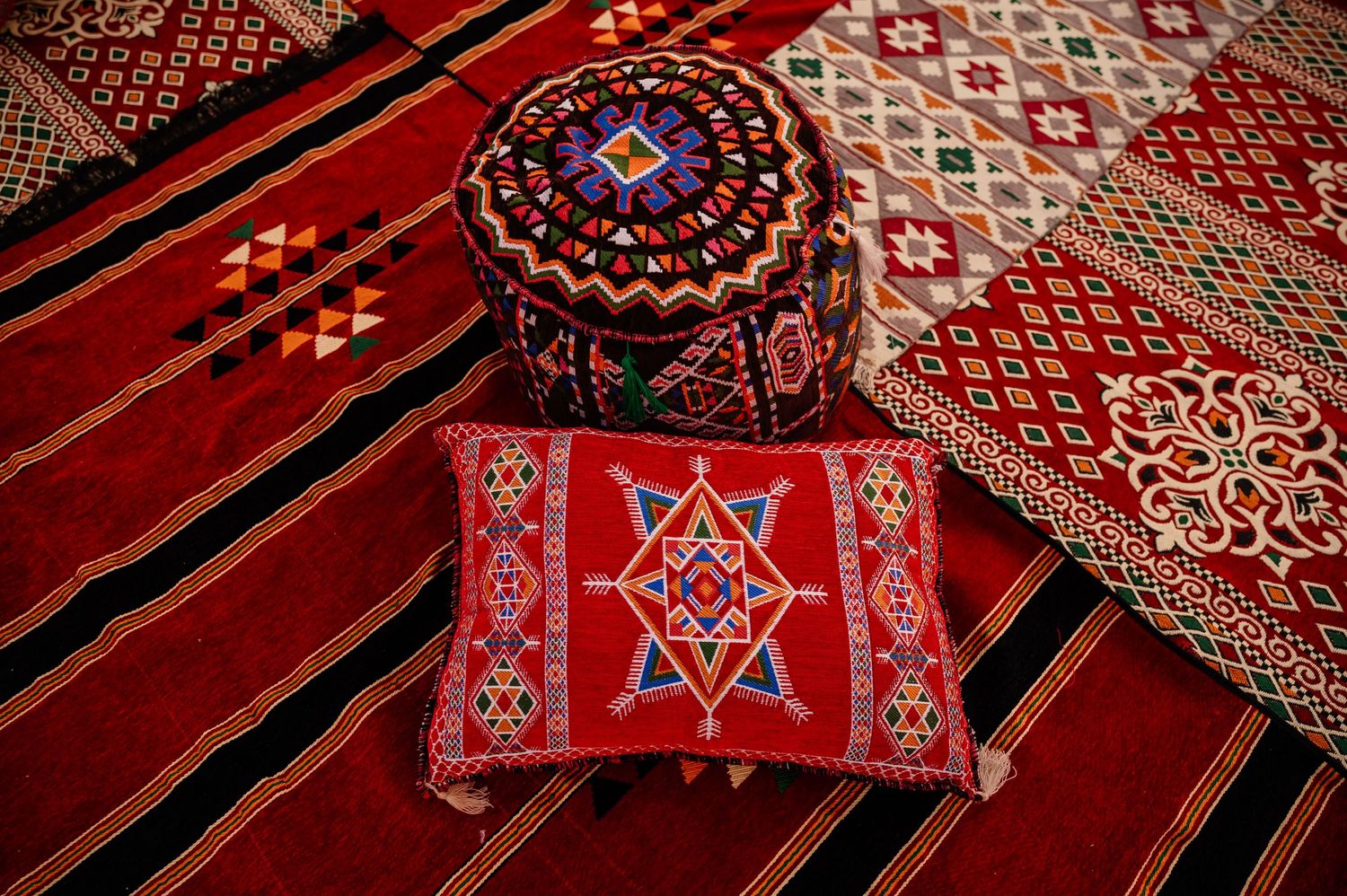 Traditional Egyptian decorative cushions and carpets with intricate geometric patterns in red.