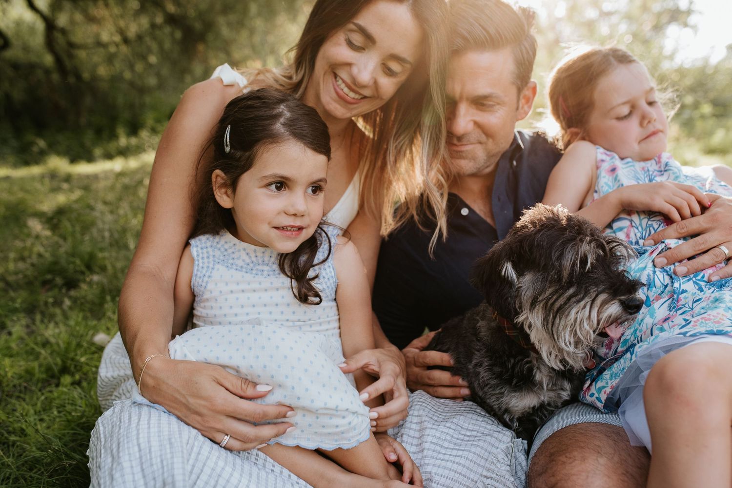 Family of four with a dog snuggling at Jericho Park in Vancouver