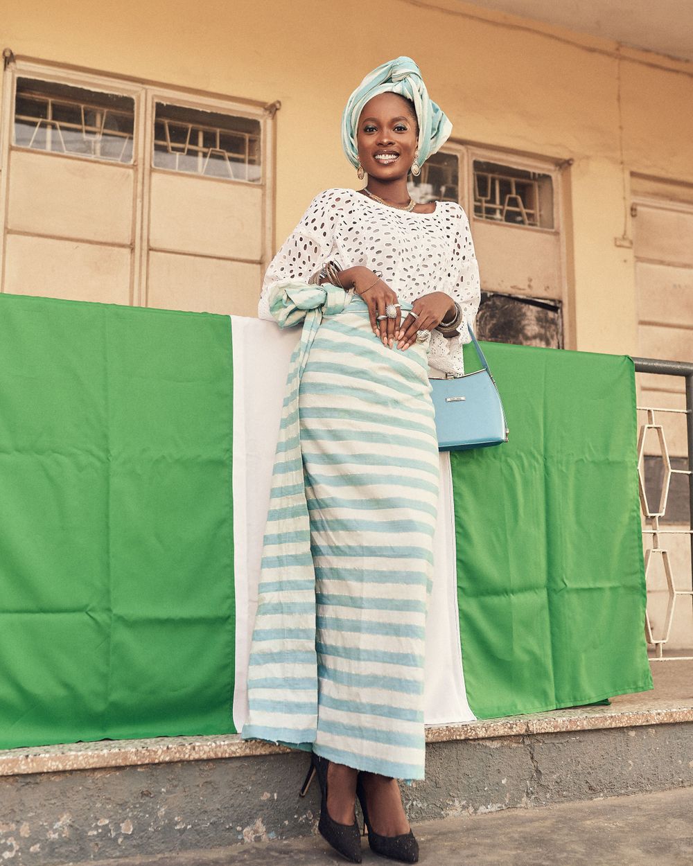 A fashion portrait in a white crochet top and striped skirt with turquoise headwrap.