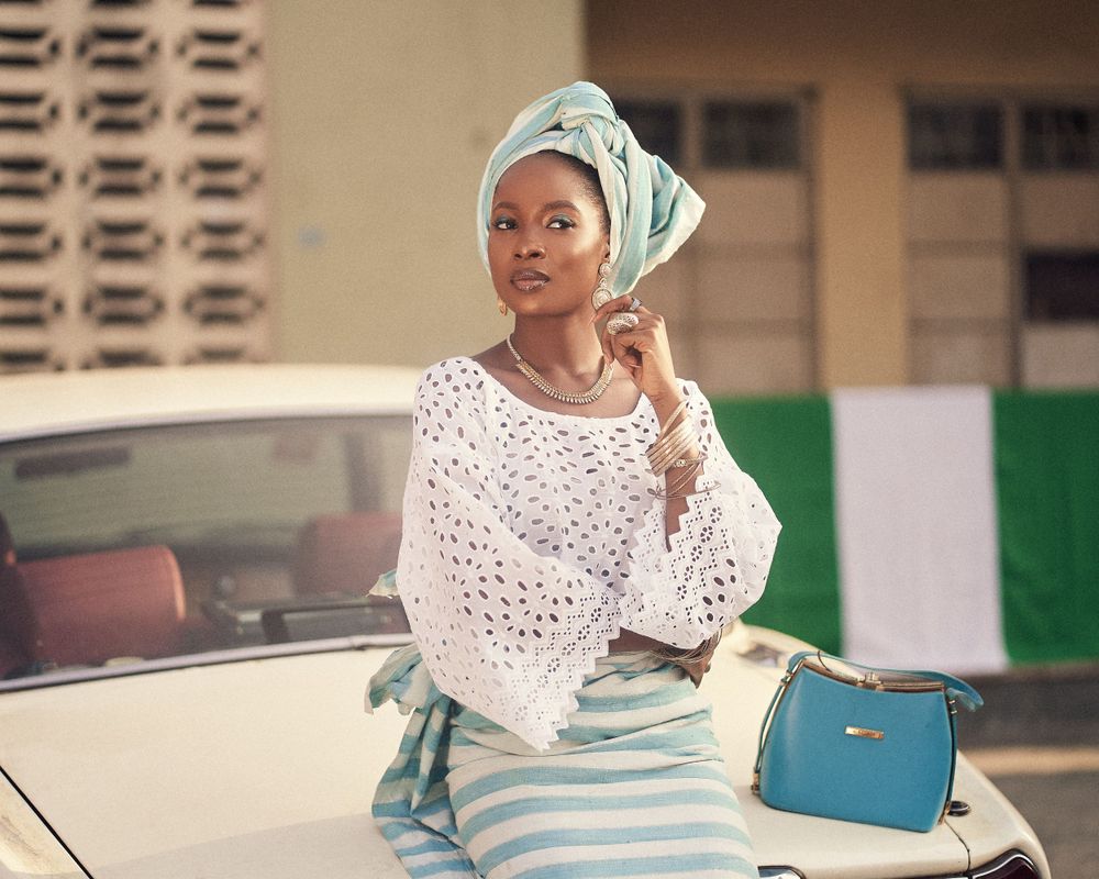 Fashionable ensemble with white lace top and mint striped skirt posed near classic car.
