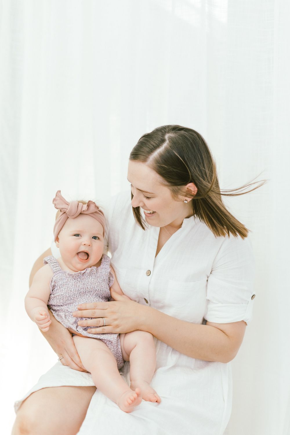 Sweet family moment captured against white backdrop in natural light photography session.
