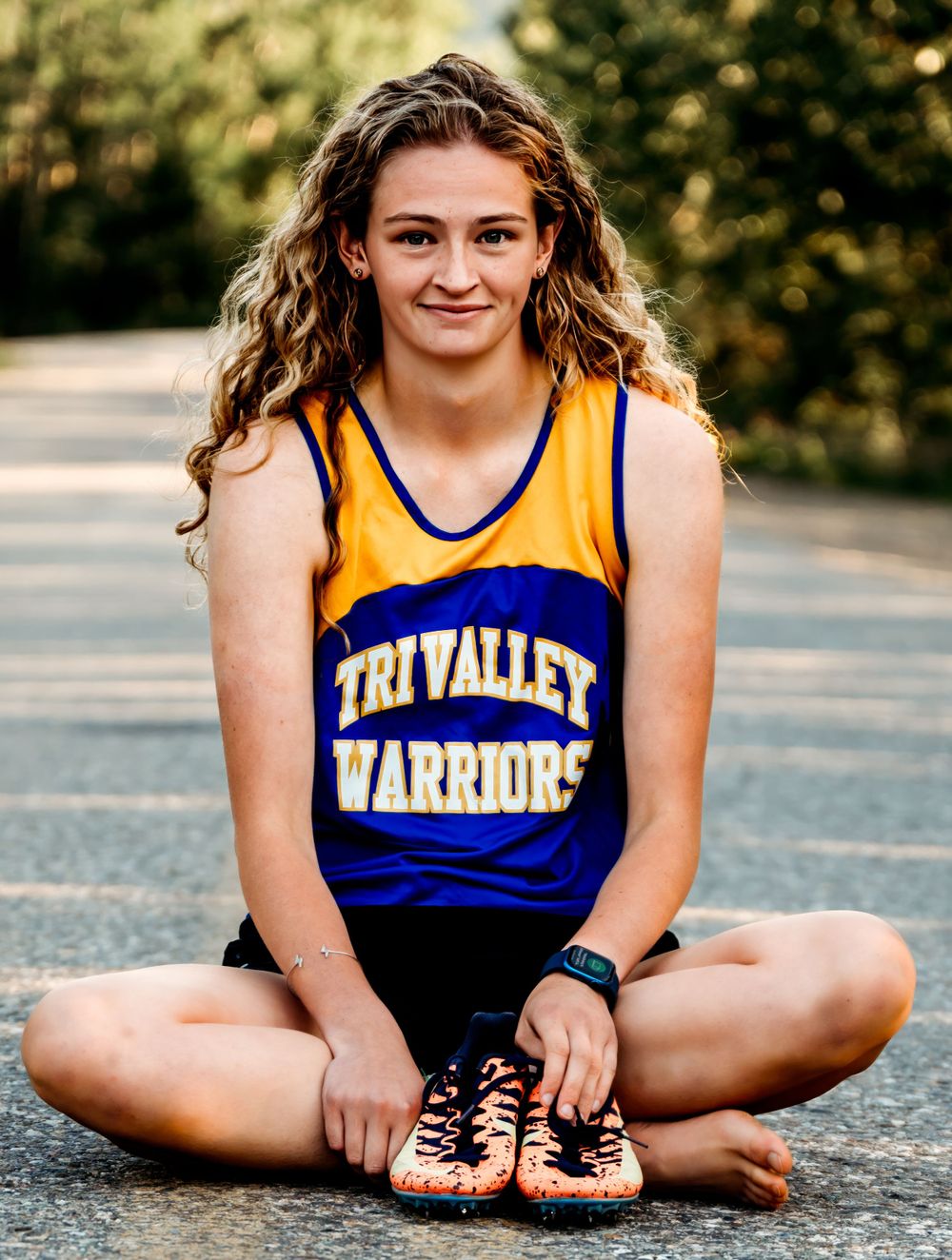Athlete seated on pavement wearing yellow and blue Tri Valley Warriors uniform.