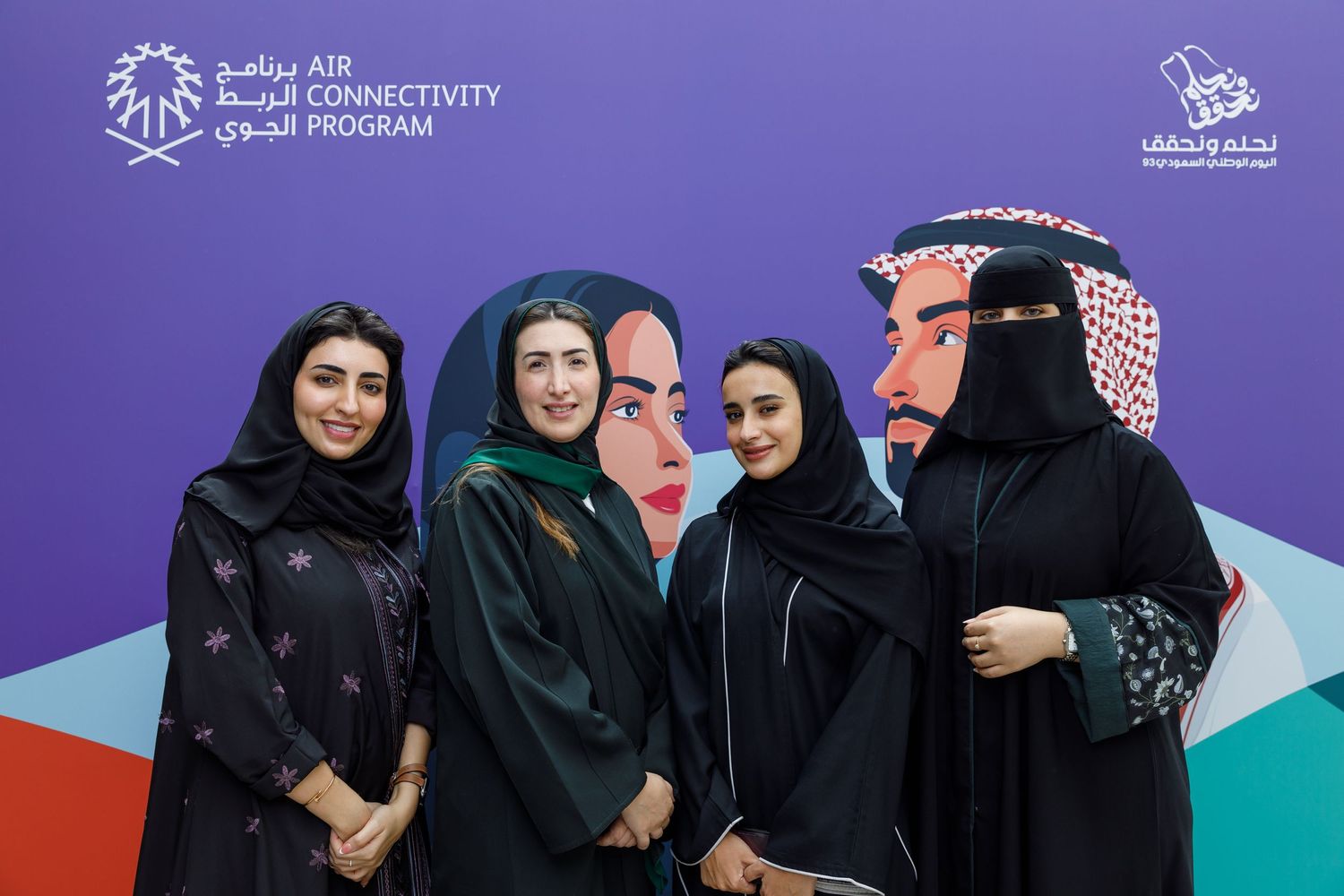A group photo of people in traditional Middle Eastern attire against a branded backdrop.