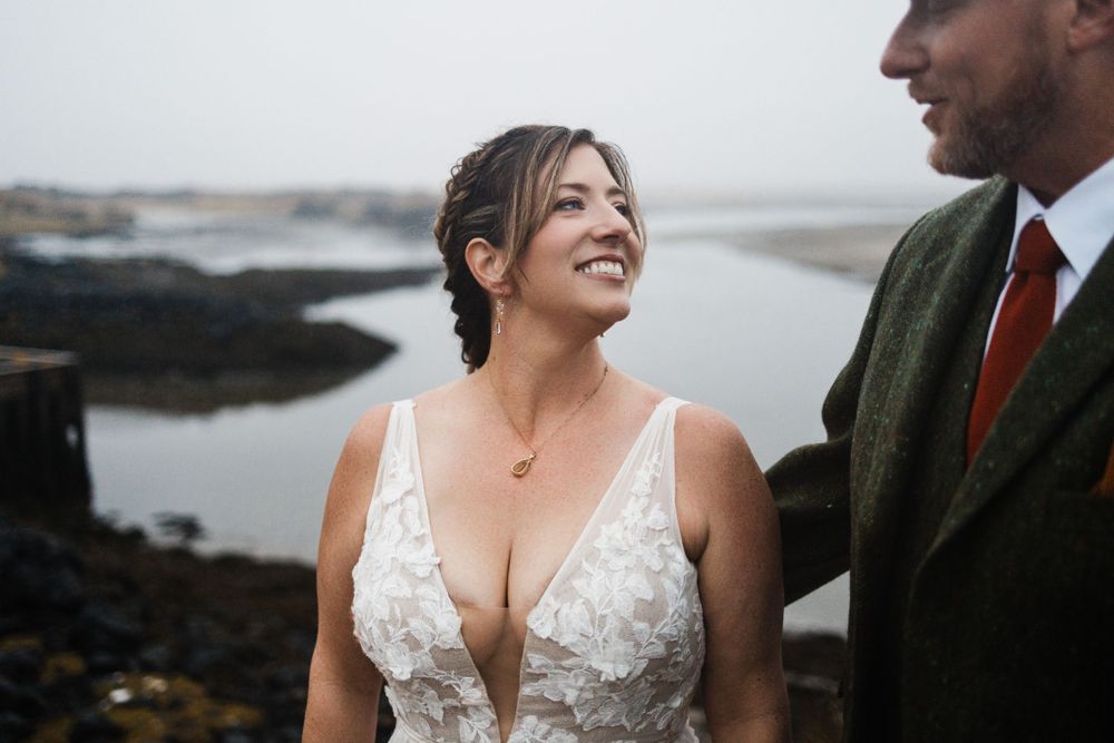 A couple shares a joyful moment against a dramatic coastal backdrop.