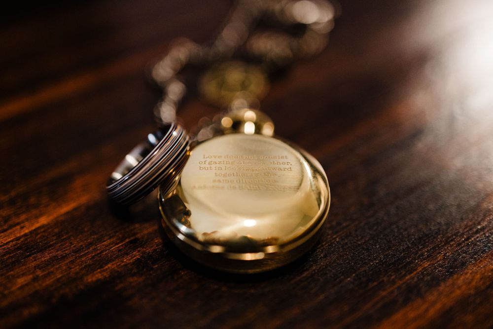 Vintage gold pocket watch rests on dark wooden surface.