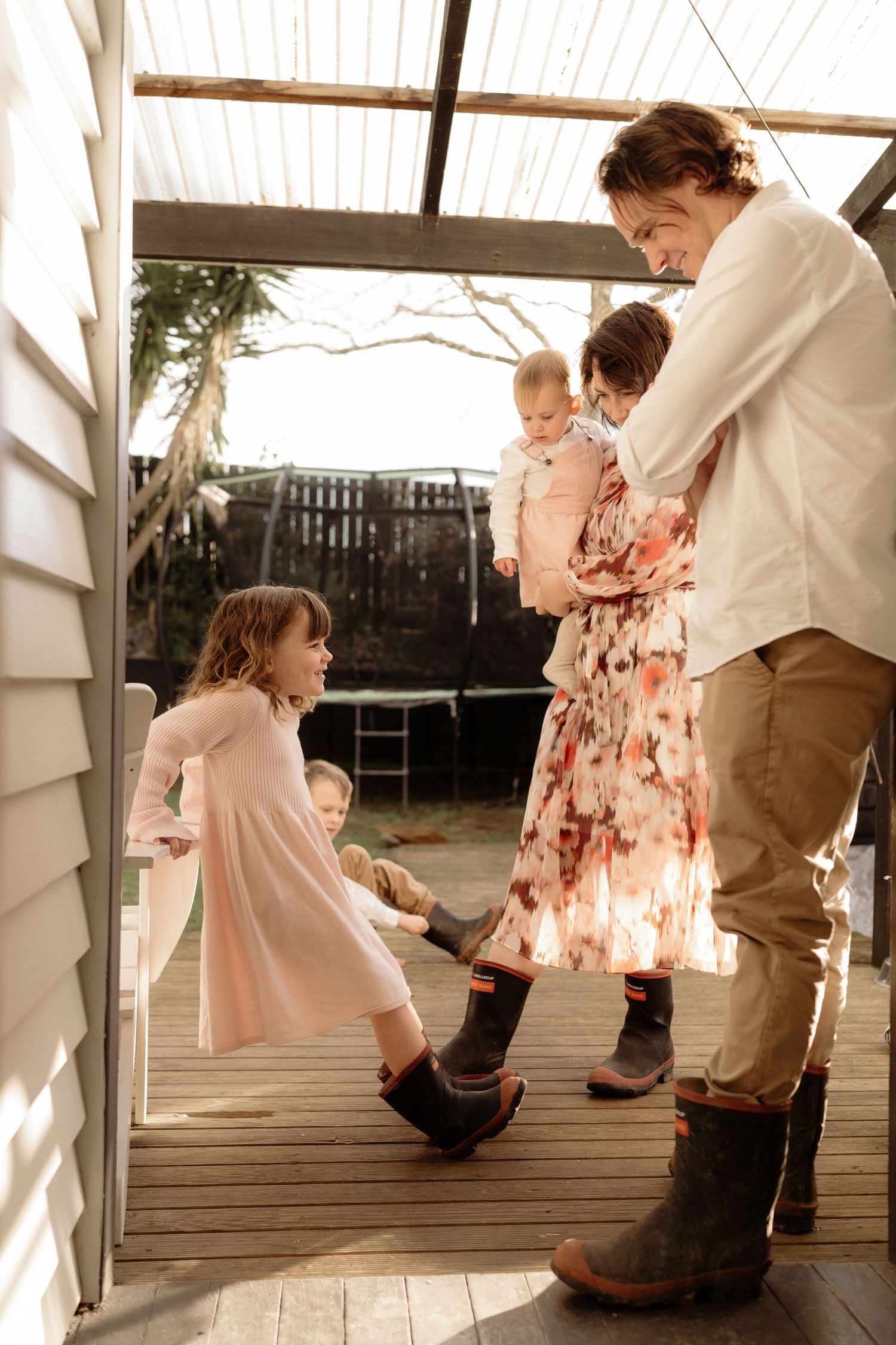 family putting on gumboots for the backyard.  Candid in home Auckland Photoshoot